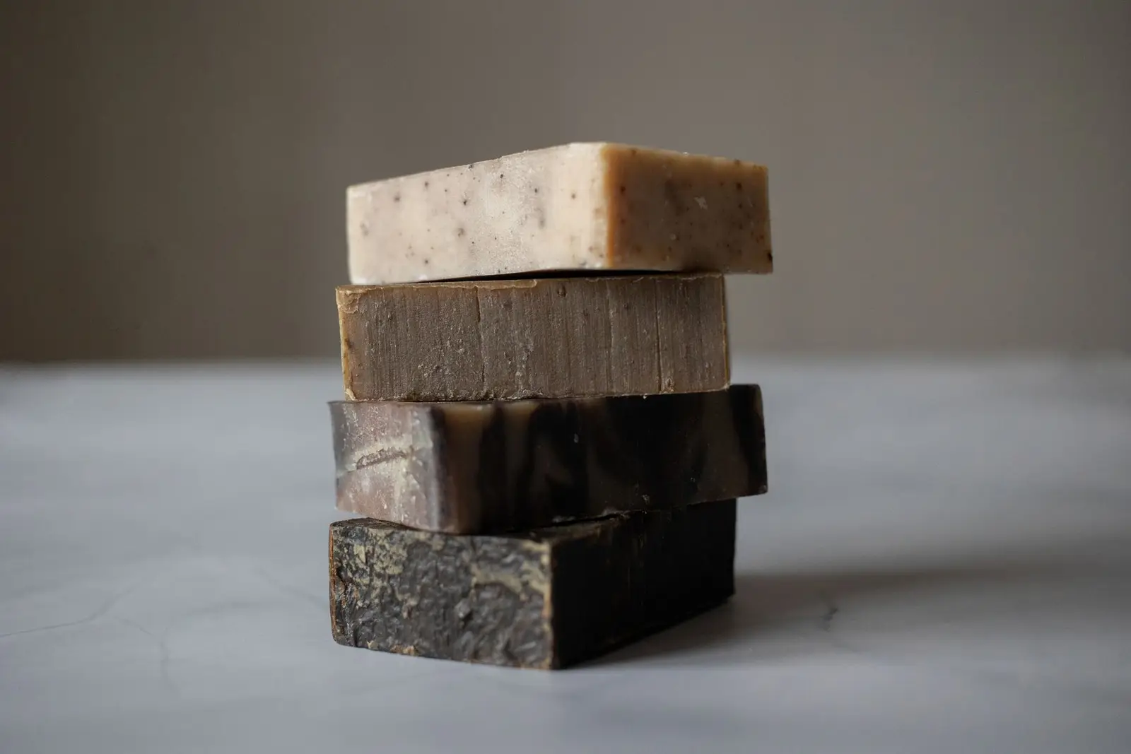 Pile de quatre savons artisanaux sur une table grise